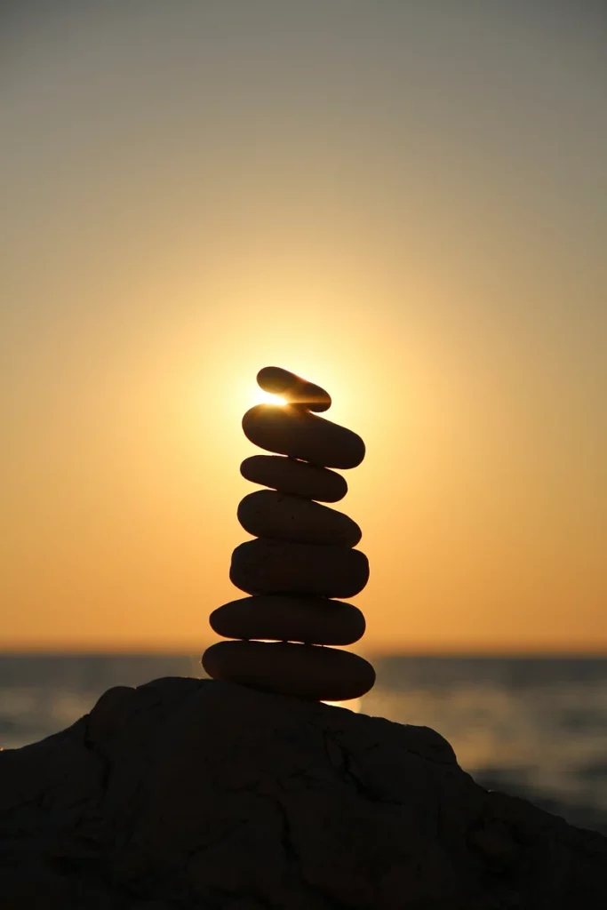 Photo apaisante d'un cairn, un empilement de galets, dans un paysage de soleil couchant.